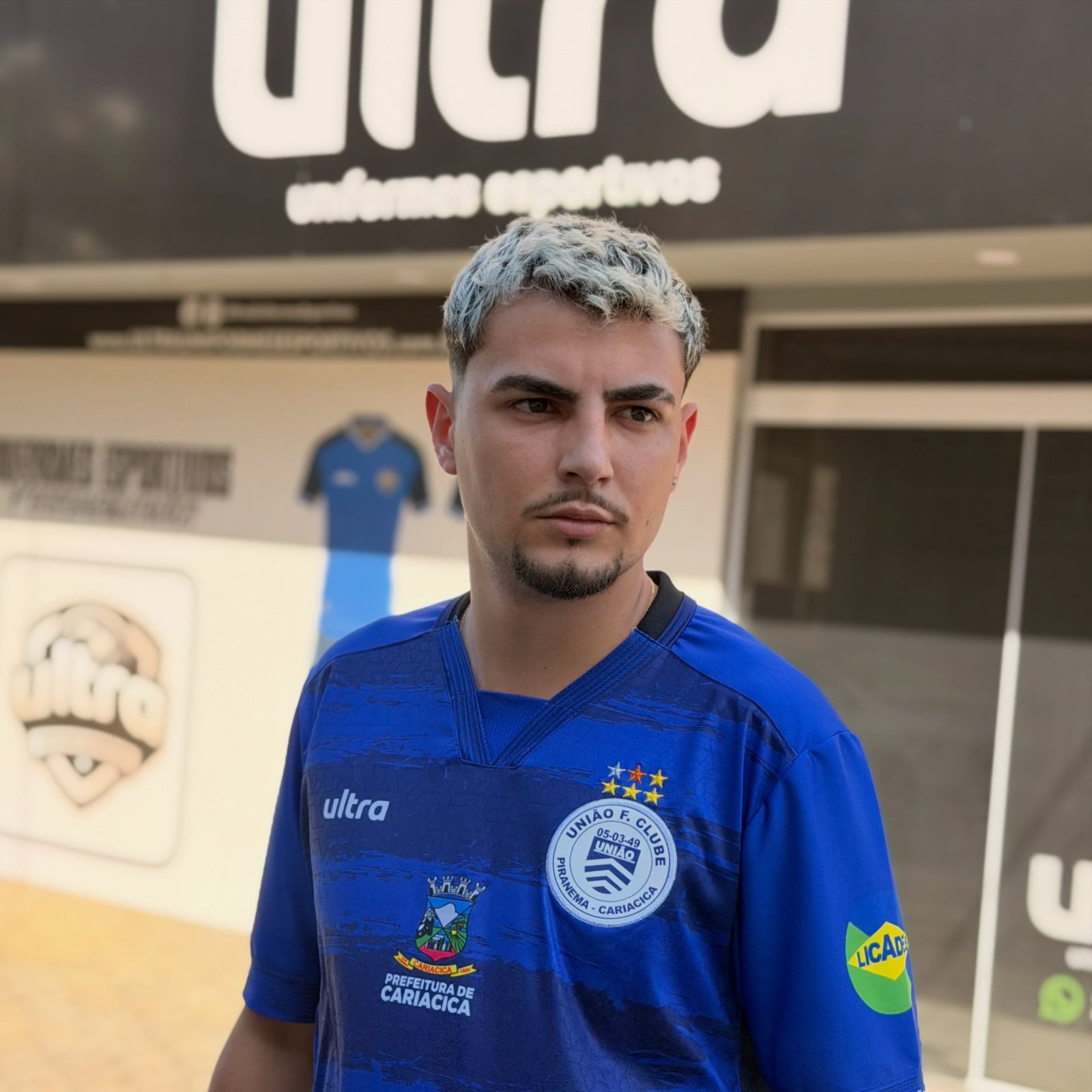 Atleta vestindo uniforme azul em frente a loja